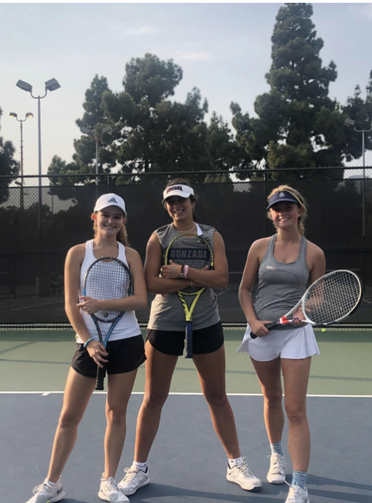 Kate Maidy, a sophomore, Mila Klostermann, a sophomore, and Chiara Tesoriero, a senior, smile during a tennis practice at Cheviot Hills. They have been working super hard this season at tennis. 