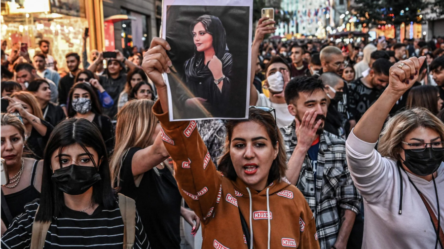 Iranian women holding pictures of Mahsa Amini and removing their hijab in protest of the Iranian government’s strict regulations on hijab. 