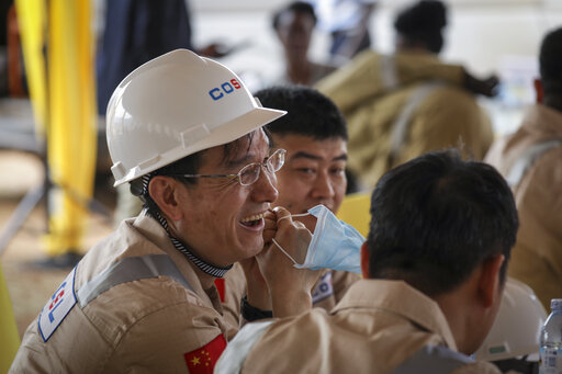 Chinese workers from China Oilfield Services Limited (COSL), a contractor for China National Offshore Oil Corporation (CNOOC), attend the inauguration of the start of drilling at the Kingfisher oil field on the shores of Lake Albert in the Kikuube district of western Uganda Tuesday, Jan. 24, 2023. Oil drilling began Tuesday at the Chinese-operated oil field and the East African country expects to start production by 2025, a government official said. (AP Photo/Hajarah Nalwadda)