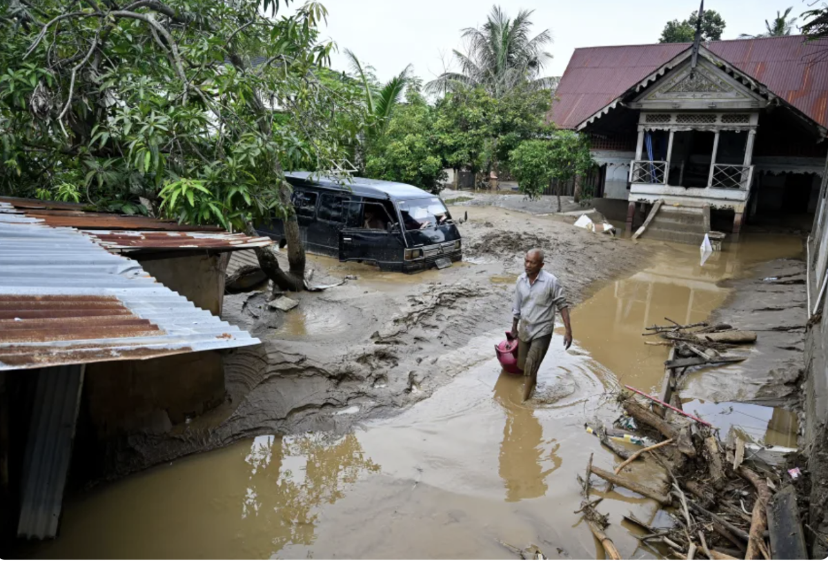 A man wades through the floodwaters following flash floods in Indonesia. Image courtesy of CNN.